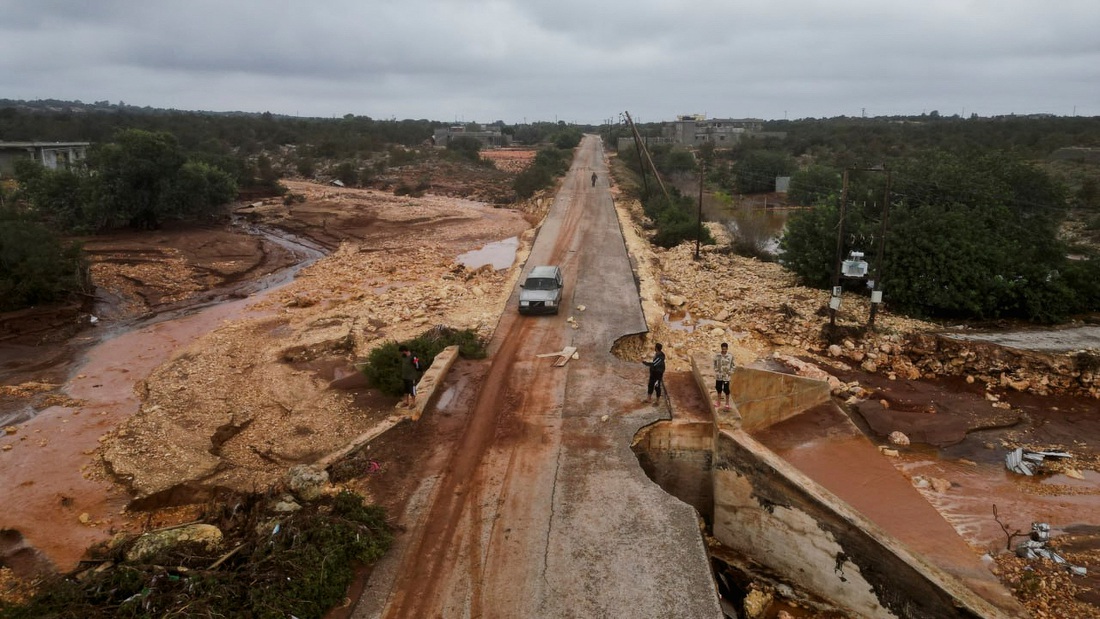 Người dân đứng trên con đường bị hư hỏng khi bão lớn đổ bộ vào thành phố Shahhat, Libya, ngày 11-9 - Ảnh: REUTERS