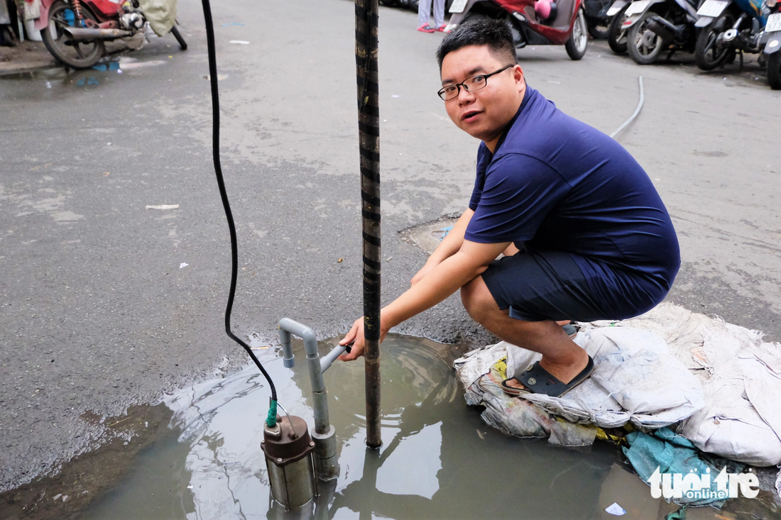 Anh Hiếu bên chiếc máy bơm làm việc hết công suất vẫn không giải quyết được vũng nước ngập trước cửa nhà