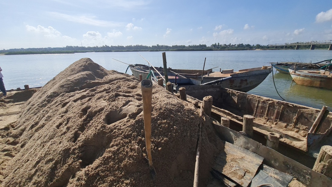 Một ụ cát vừa được chuyển từ máy hút lên bờ, bên cạnh nhiều ghe hút cát trái phép công khai đậu đỗ - Ảnh: TRẦN MAI