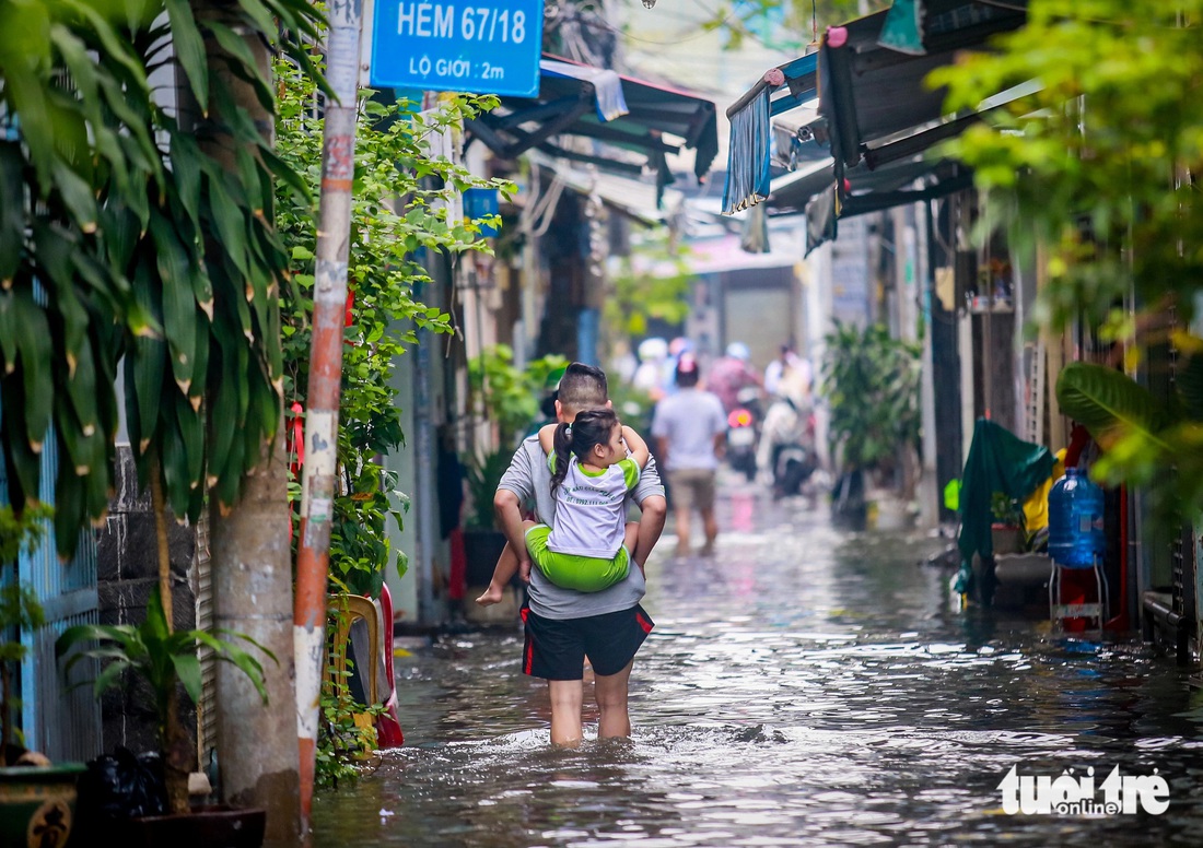 Quận 7 ngập cả mét vì triều cường, người phải ở khách sạn, người cõng con đi học - Ảnh 6.