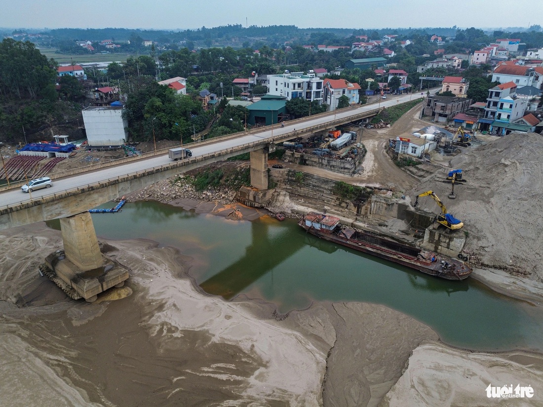 Theo Cục Thủy lợi, nguyên nhân chính dẫn đến lòng sông dưới chân cầu Trung Hà bắc qua sông Đà (nối Hà Nội với Phú Thọ) bị xói lở nói riêng và hạ thấp lòng dẫn hệ thống sông Hồng - Thái Bình nói chung là do khai thác cát. Trong ảnh là một bãi tập kết cát ngay sát chân cầu - Ảnh: HỒNG QUANG