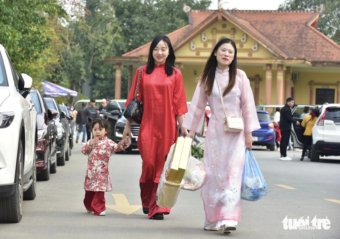 Bé gái cùng mẹ và cô xúng xính áo dài mang lễ vật lên Đền Hùng chiều mùng 1 Tết - Ảnh: T.T.D.