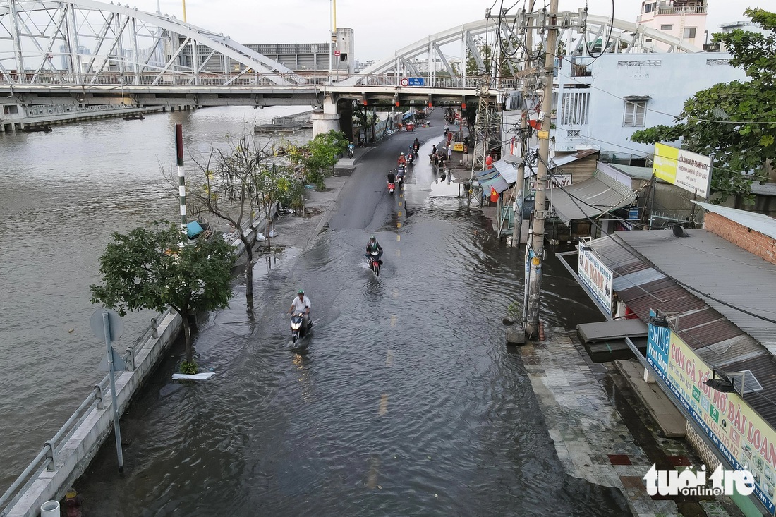 Nước từ sông và các ống cống ồ ạt tràn ra khiến tuyến đường Trần Xuân Soạn ngập vào mùng 3 Tết, việc đi lại của người dân gặp khó khăn