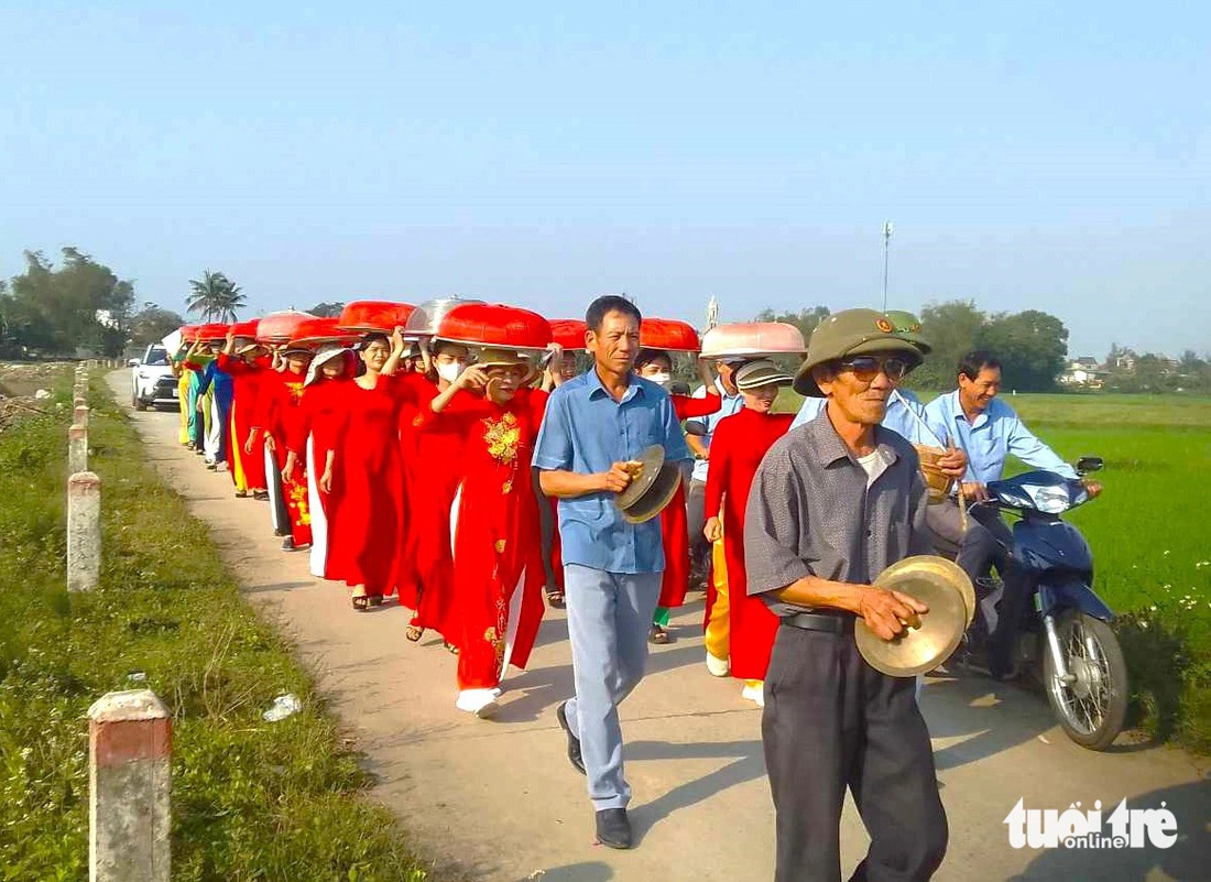 Quá trình mang lễ về đền thờ diễn ra rất nghiêm túc. Người được chọn mang lễ với đàn ông thì mặc áo sơ mi, phụ nữ mặc áo dài truyền thống. Lễ mang về đền được đội trên đầu, có những thôn phải đi bộ cả cây số mới đưa lễ về đến đền thờ - Ảnh: LÊ MINH