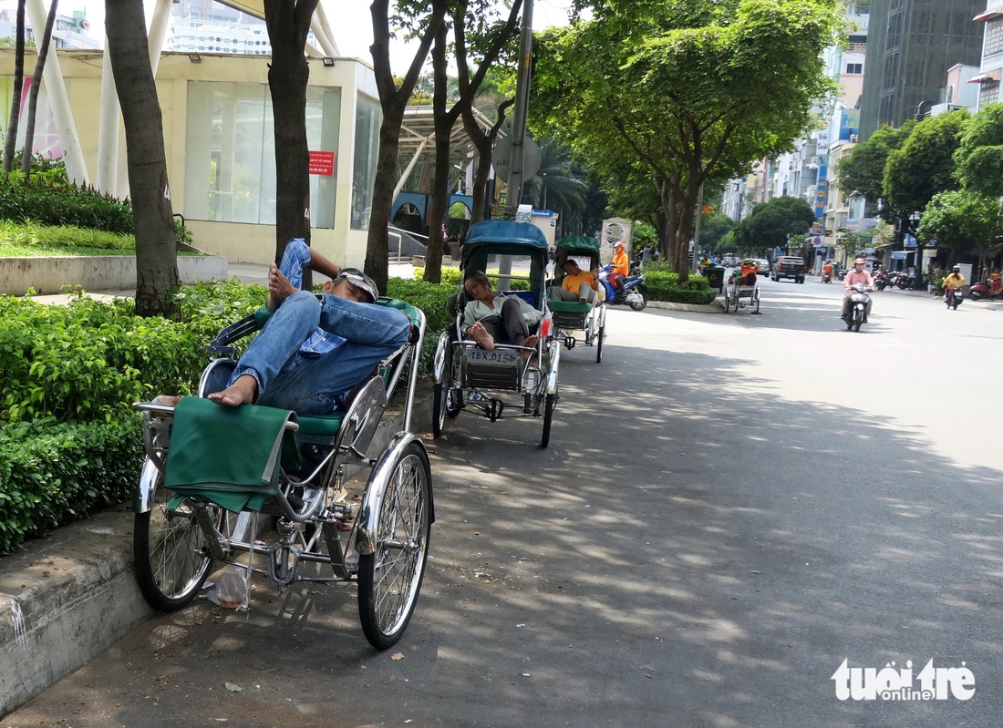 Các bác xích lô nghỉ ngơi đợi khách dọc theo hàng cây trên đường Lê Lai, quận 1.