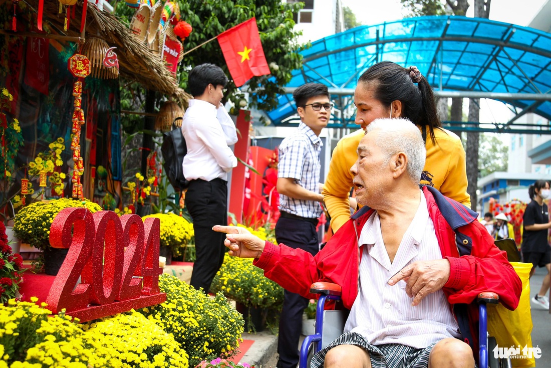 Chị Như Thủy (quê Vĩnh Long) đẩy xe cùng cha dạo quanh đường hoa - Ảnh: PHƯƠNG QUYÊN