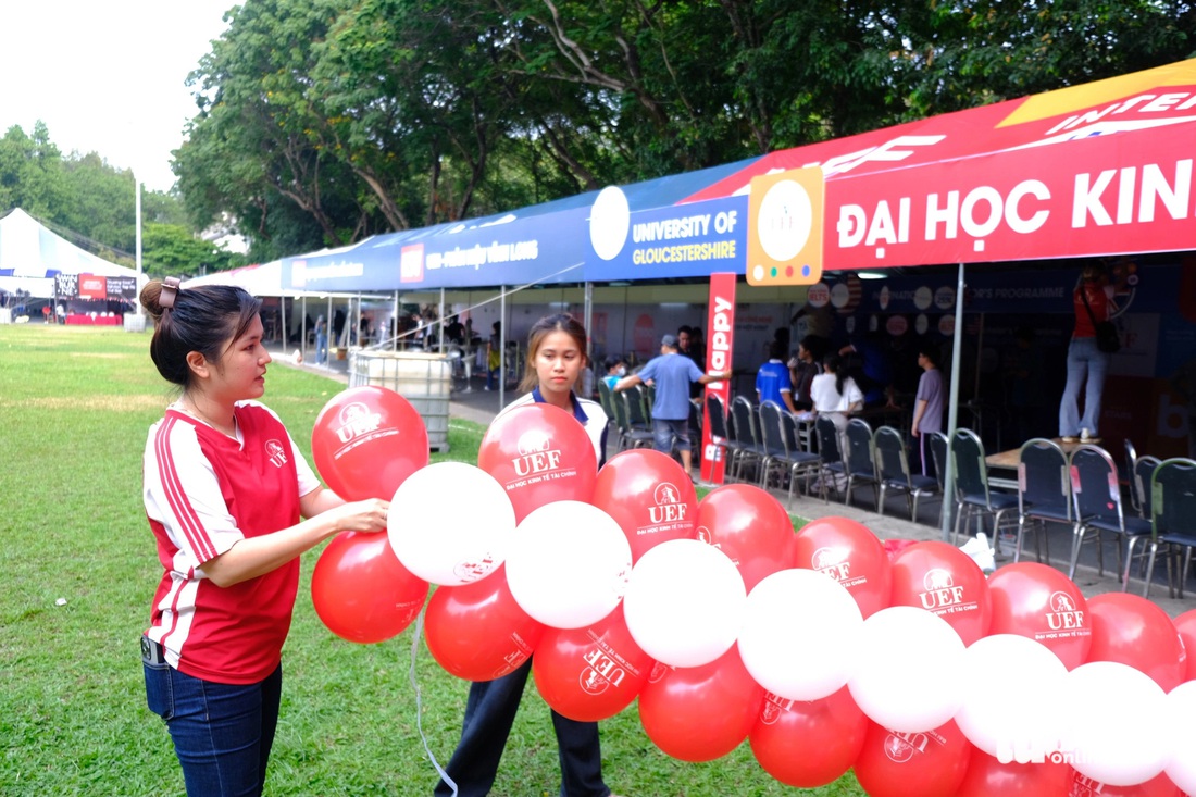 Nhân viên Trung tâm tư vấn tuyển sinh Trường đại học Kinh tế - Tài chính TP.HCM trang trí gian hàng - Ảnh: NGỌC PHƯỢNG