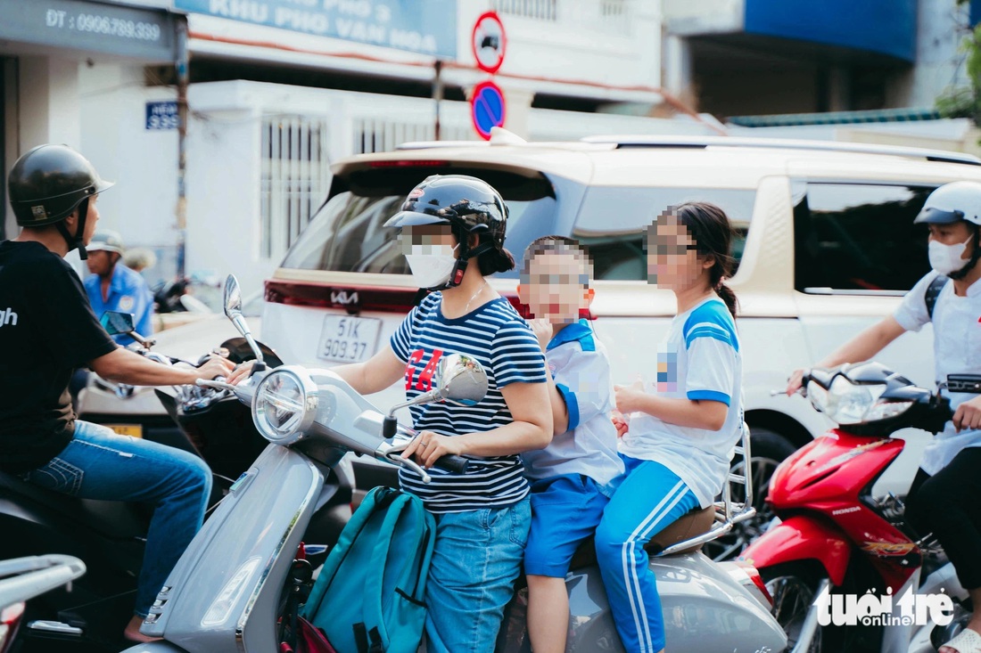 Nhiều phụ huynh không chịu mang mũ bảo hiểm để con đội gây mất an toàn khi tham gia giao thông - Ảnh: THANH HIỆP