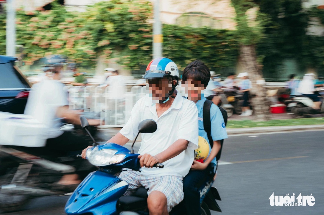 Học sinh được phụ huynh mang mũ bảo hiểm trên tay nhưng cũng chẳng thèm đội - Ảnh: THANH HIỆP