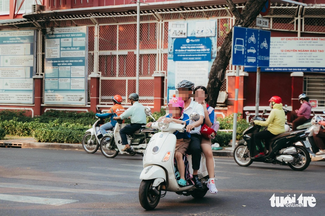 Phụ huynh mang mũ bảo hiểm cho em nhưng quên mang cho chị - Ảnh: THANH HIỆP