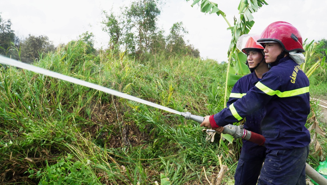 Lực lượng chữa cháy vẫn đang túc trực để dập tắt đám cháy - Ảnh: THANH HUYỀN