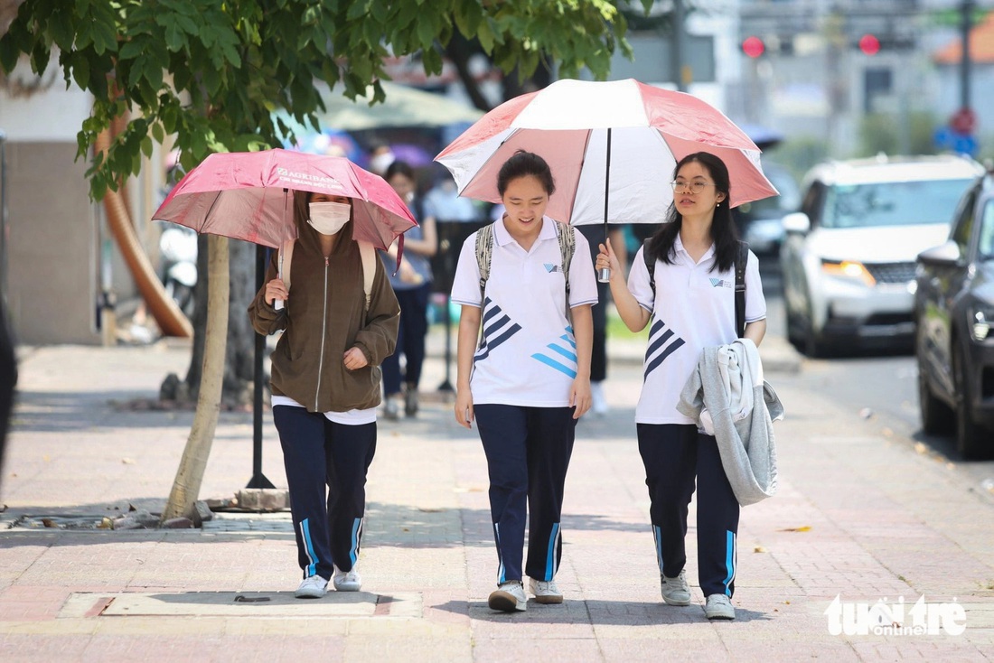 Nhóm sinh viên Đại học Khoa học xã hội và Nhân văn ra về sau khi vượt nắng tham gia hoạt động trên trường. "Em quên mang theo áo khoác, phải tranh thủ đi về nhanh chứ không cháy nắng mất" - bạn Thảo (ở giữa) nói - Ảnh: PHƯƠNG QUYÊN