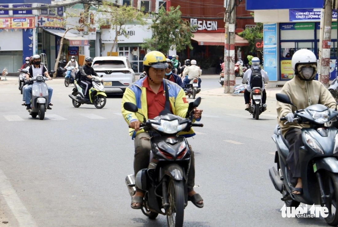 Một tài xế xe ôm công nghệ "dán mắt" vào điện thoại trên đường Hoàng Diệu 2 (TP Thủ Đức) khi đang lái xe - Ảnh: THU DUNG