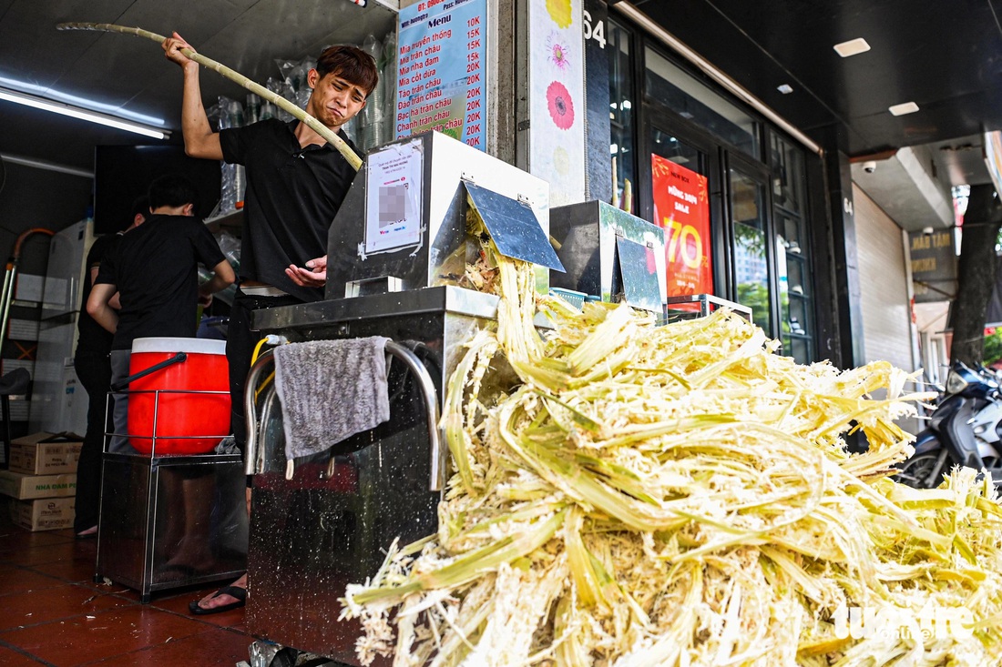 Một quán nước mía trên đường Nguyễn Trãi hoạt động hết công suất. Chủ quán cho hay trời nắng nóng khiến mức tiêu thụ tăng 2-3 lần - Ảnh: HỒNG QUANG