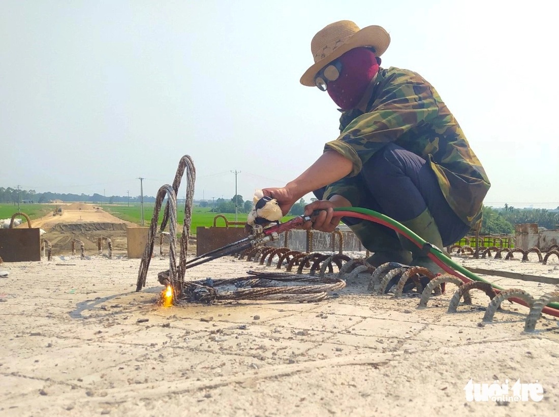 Anh Trần Khánh Hòa (ngụ tỉnh Nam Định) là công nhân phụ trách hàn xì mặt cầu vượt tại dự án cao tốc Bắc - Nam, cho biết công việc này khá nóng nên gặp những ngày nhiệt độ cao, người anh nóng bức, mồ hôi đổ ra nhiều hơn. Dù nóng nhưng khi làm việc anh vẫn phải trùm kín mặt để tránh nắng và bụi hàn xì bắn vào - Ảnh: LÊ MINH