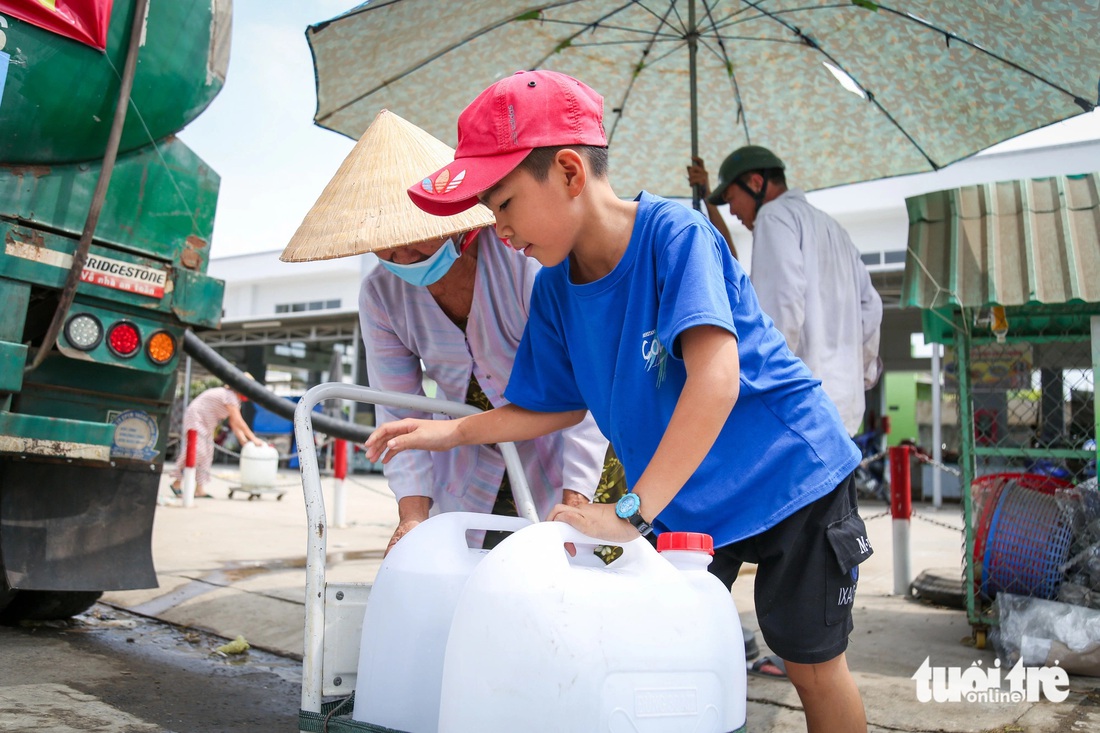 Em Lê Quốc Huy đẩy xe phụ bà nội đi lấy nước khoe: “Từ sáng giờ con lấy được 6 thùng rồi”