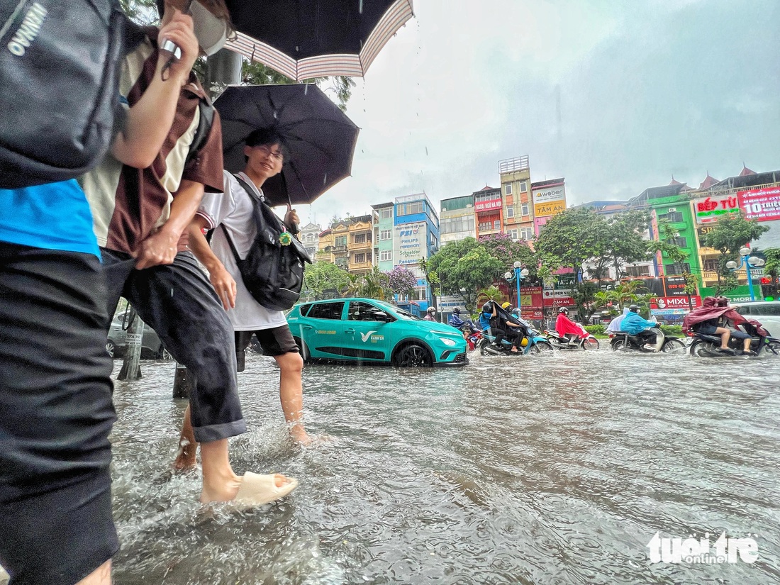 Nhiều sinh viên sau giờ tan học phải lội nước ngập về nhà - Ảnh: PHẠM TUẤN