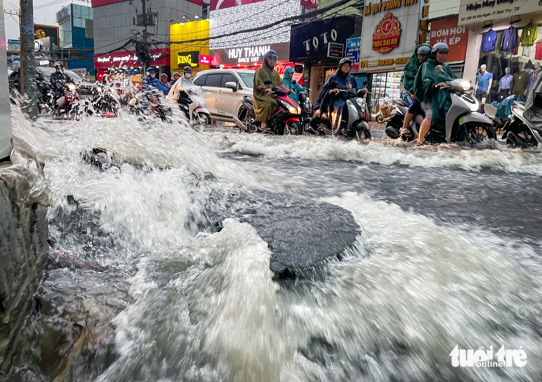 Chiều 15-5, mưa gây ngập và chảy xối xả trên đường Võ Văn Ngân (TP Thủ Đức) khiến người đi xe máy té ngã và các mảng nhựa đường bong tróc - Ảnh: CHÂU TUẤN