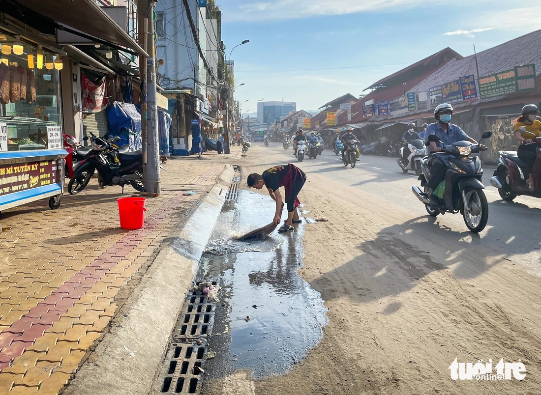 Người dân quét dọn phía trước nhà vì bùn đất "tấn công" - Ảnh: LÊ PHAN