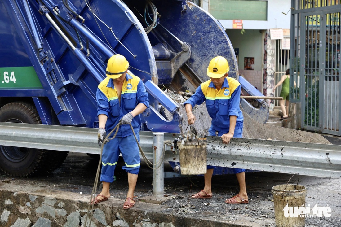 Có đoạn sâu, rào chắn nên công nhân phải xách từng xô rác một đổ lên xe - Ảnh: NGỌC QUÝ