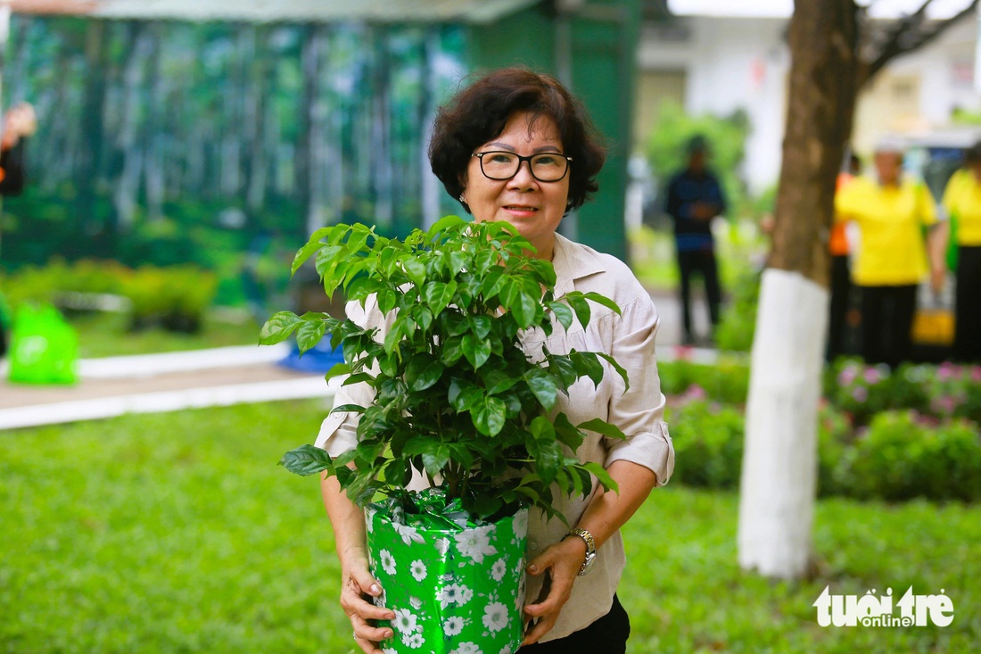 Bà Nguyễn Thị Kim Dung, ngụ đường Phan Xích Long, với chậu cây được UBND quận Phú Nhuận tặng. Bà Dung cho biết trước đây khi được vận động bà thấy tham gia cũng không có kết quả gì. Sau thời gian thấy cảnh quan, mảng xanh tốt hơn, bà Dung thay đổi quan điểm và rất ủng hộ. Bà cho tháo dỡ mái che, dù và trồng thêm cây xanh tại nơi bà kinh doanh để tăng mỹ quan - Ảnh: LÊ PHAN