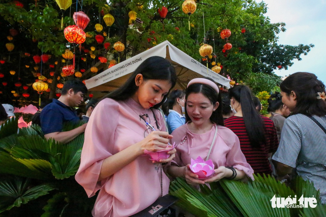 Anh Thư (trái) cùng bạn từ quận 10 đến sớm để có vị trí đẹp. Thư viết lên hoa đăng lời chúc cầu mong bình an, sức khỏe cho người thân và bạn bè xung quanh