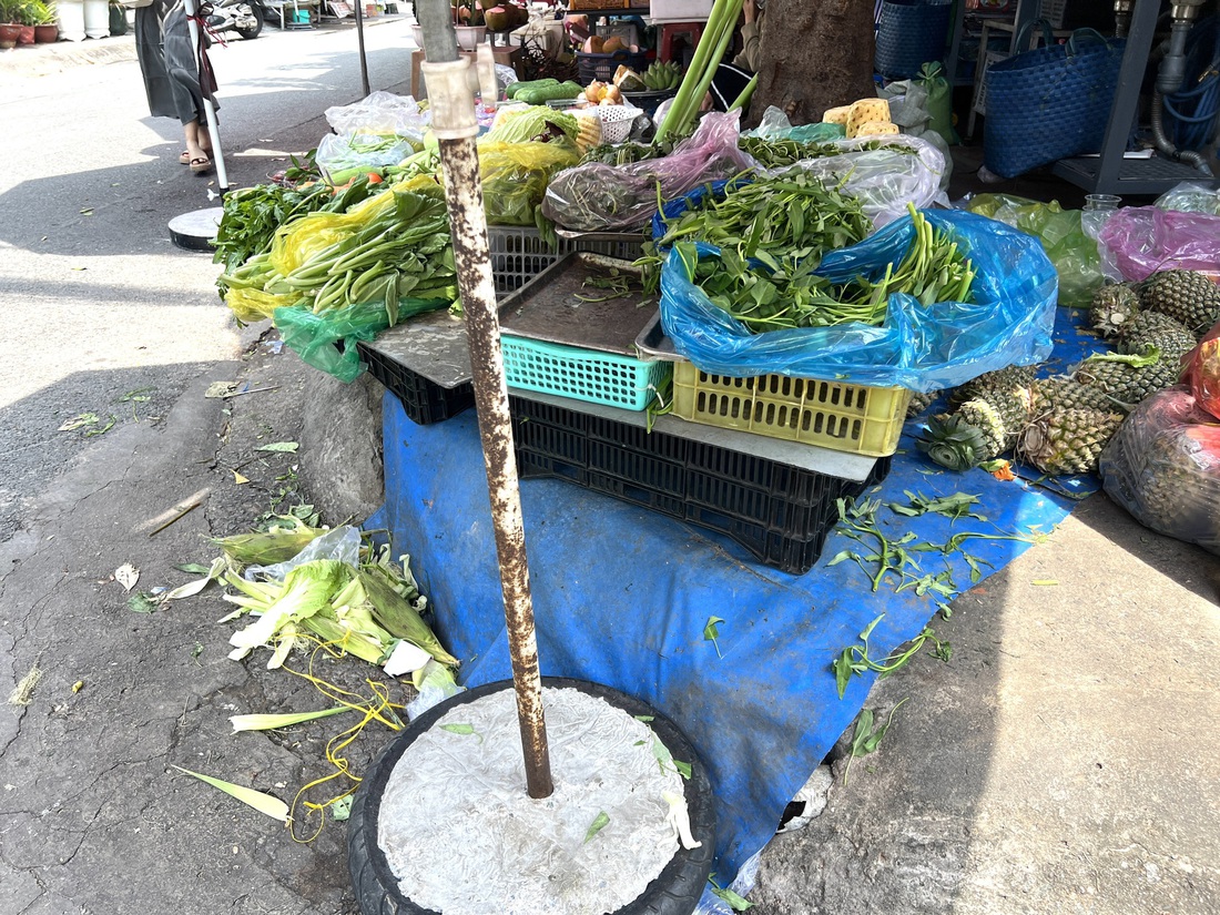 Một người buôn bán trong cư xá Chu Văn An, quận Bình Thạnh dùng bạt che miệng cống rồi... xả rác xung quanh - Ảnh: XUÂN ĐOÀN