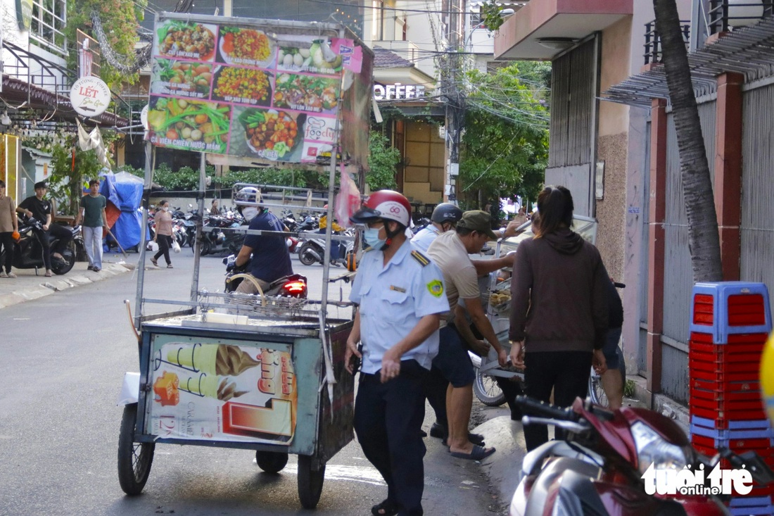 Một trường hợp vội vàng thu gom đồ "trốn" đô thị nhưng không kịp, bị lập biên bản và bị thu giữ dụng cụ buôn bán - Ảnh: TIẾN QUỐC