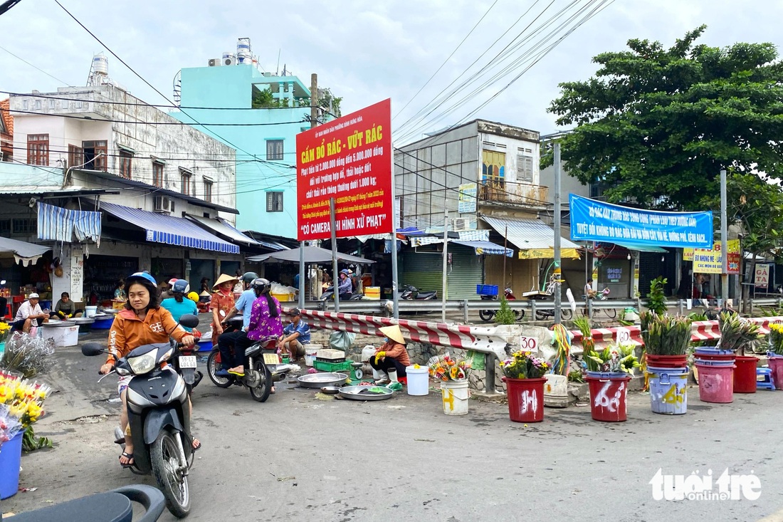 Mặc dù đã có biển cấm vứt rác, tụ tập dọc tuyến kênh, nhưng nhiều người dân vẫn bất chấp buôn bán vào chiều tối - Ảnh: TIẾN QUỐC