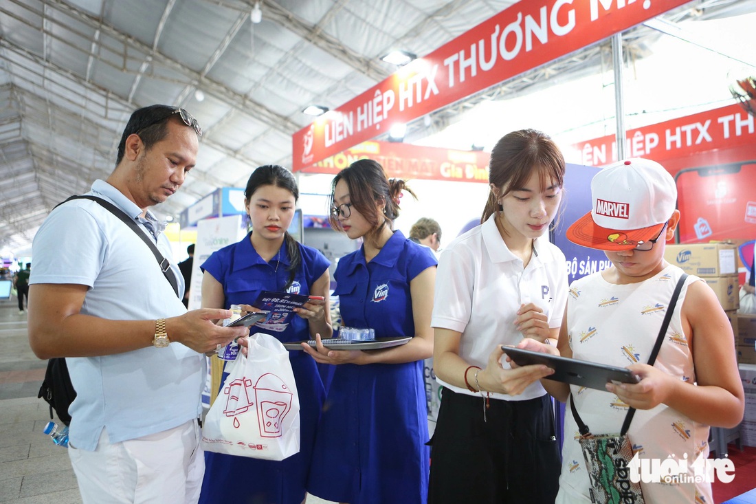 Anh Hoàng Hiệp (quận 7) cùng con trai trải nghiệm tại gian hàng HTX Thương mại TP.HCM. “Hai ngày cuối tuần tôi sẽ cùng gia đình quay lại lễ hội để tham gia nhiều hoạt động hơn”, anh Hiệp nói - Ảnh: PHƯƠNG QUYÊN