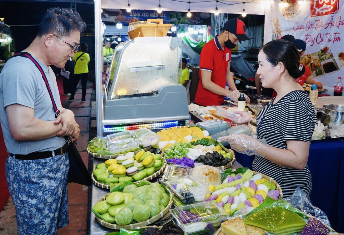 Ông Hishiro (du khách Nhật) đang chọn những loại bánh dân gian của Việt Nam để thưởng thức - Ảnh: THANH HIỆP