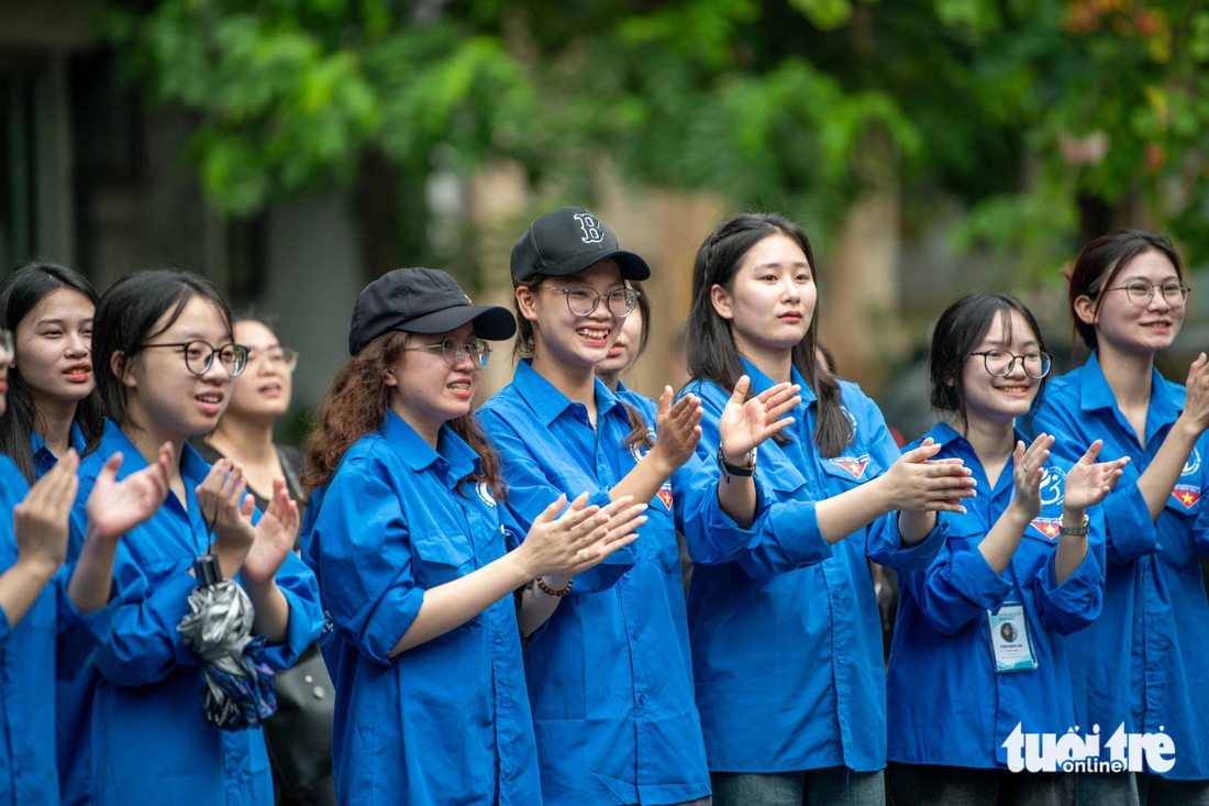 Sinh viên tình nguyện vỗ tay chúc mừng các thí sinh sau khi hoàn thành môn văn - Ảnh: NAM TRẦN