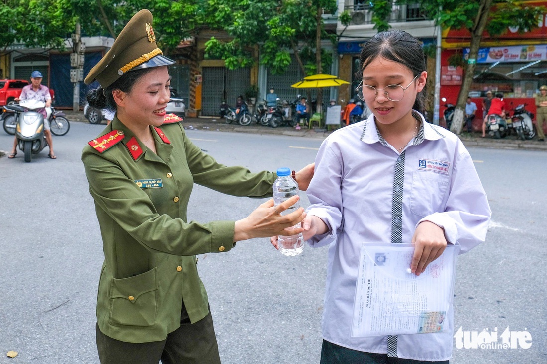 Đoàn viên Công an tỉnh Bắc Ninh tiếp nước, động viên thí sinh tại điểm Trường THPT Hoàng Quốc Việt, TP Bắc Ninh trong tiết trời nắng mưa thất thường của miền Bắc. Điểm trường này có 444 thí sinh dự thi - Ảnh: HÀ QUÂN