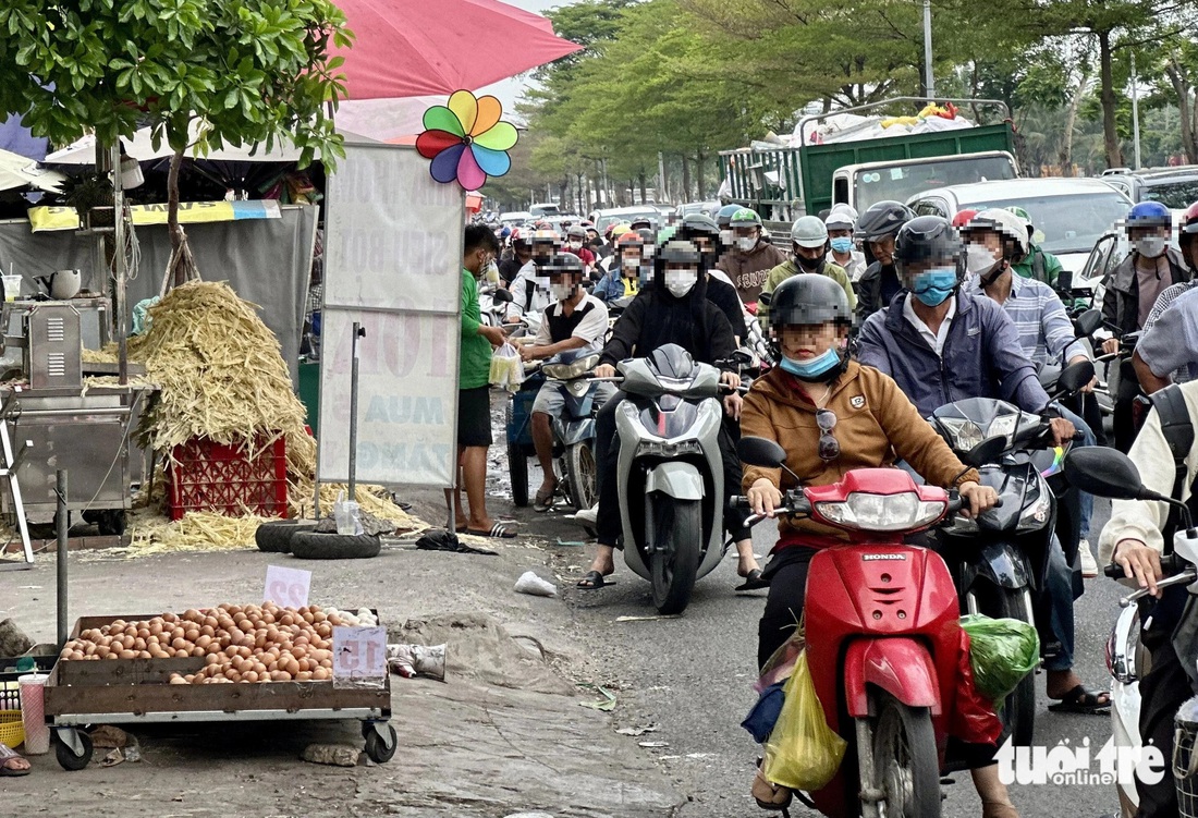 Nhiều người thản nhiên đứng dưới lòng đường mua hàng mặc kệ dòng xe chen chúc phía sau - Ảnh: NGỌC QUÝ