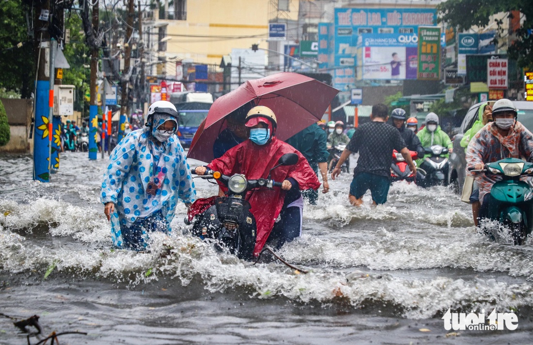 Mưa gây ngập, nước tạo thành sóng xô người đi xe máy trên đường Đỗ Xuân Hợp (TP Thủ Đức). Ghi nhận lúc 13h ngày 7-6 - Ảnh: CHÂU TUẤN