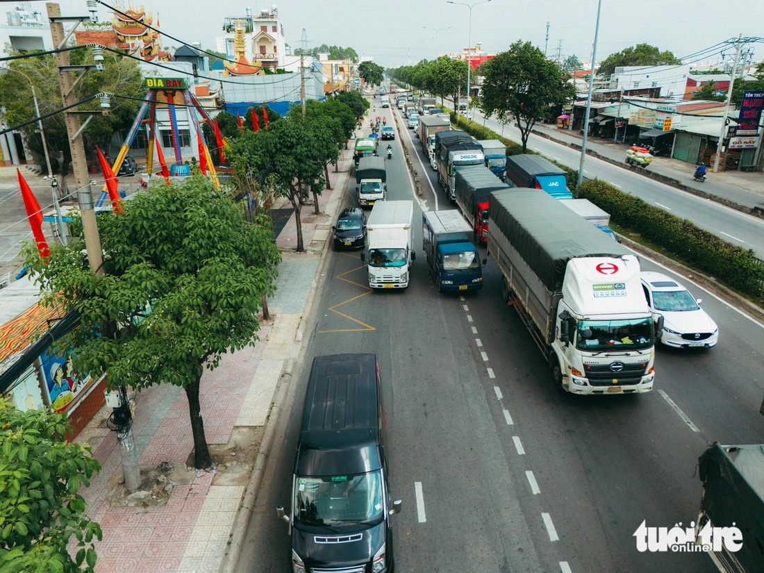 Xe khách, xe tải nối đuôi nhau đi vào làn xe máy trên quốc lộ 22 (đoạn trước cổng Trung tâm Văn hóa quận 12) - Ảnh: THANH HIỆP