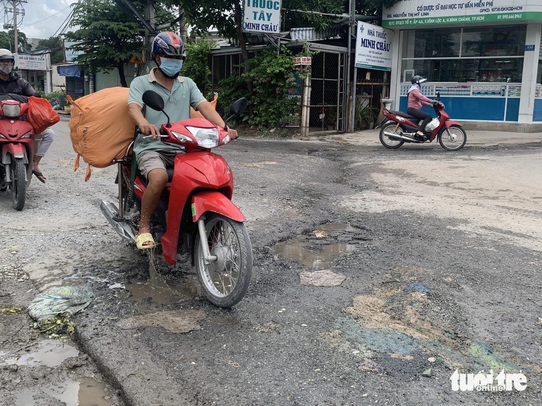 Người dân phải đi sát lề đường trên đường Phạm Văn Sáng (xã Vĩnh Lộc A, huyện Bình Chánh) để né tránh những “ổ gà” - Ảnh: KSOR QUÝ