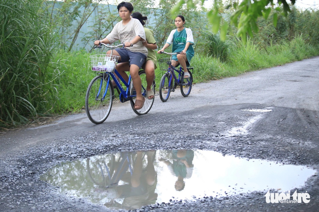 Trẻ em đi trên con đường đầy những “hố bom” trên đường Muồng Tím (phường Cát Lái, TP Thủ Đức) - Ảnh: KSOR QUÝ