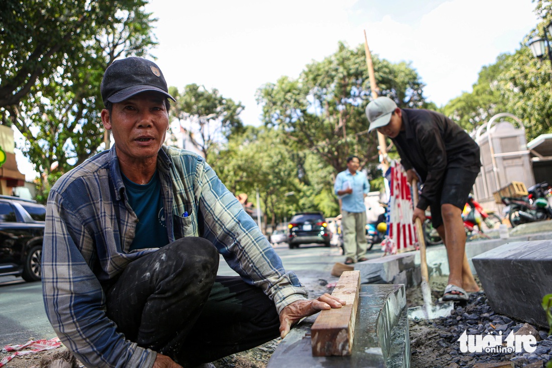 Anh Minh Toàn đào rãnh để đặt các khối đá xanh dùng làm nền chắn vỉa hè. "Công trình hoàn thành, người dân đi lại thuận tiện hơn, đường sá cũng đẹp hơn nên anh em ai cũng cố gắng làm tốt phần việc của mình" - anh Toàn chia sẻ.