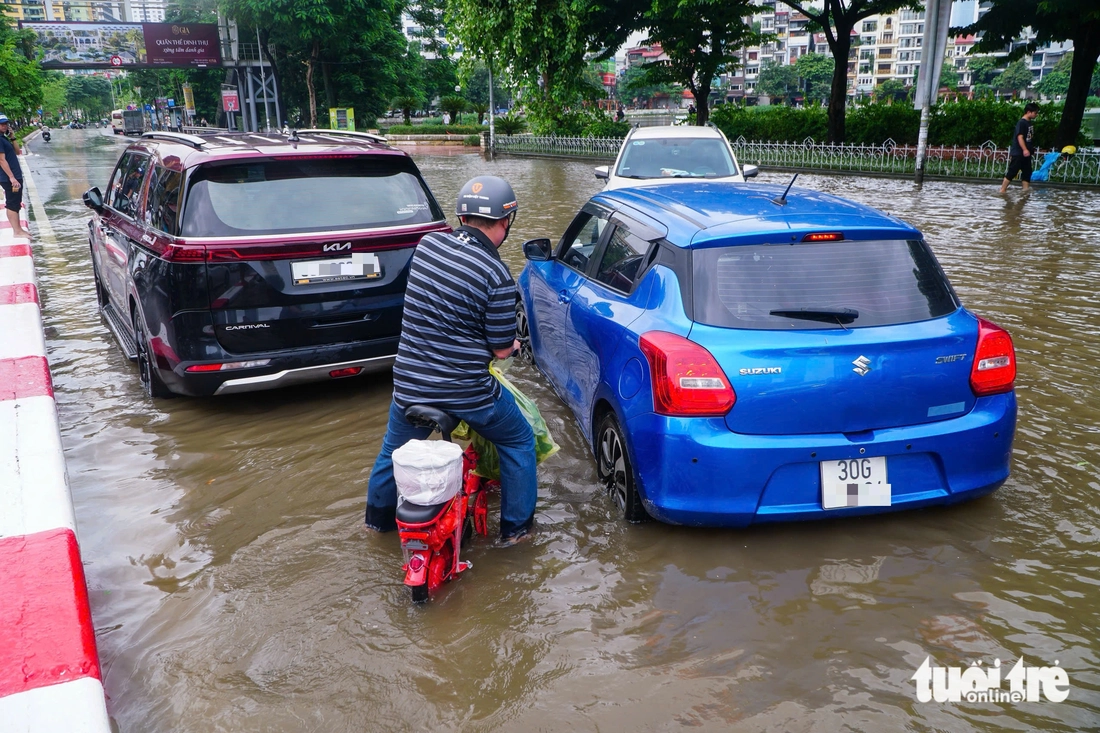 Hà Nội vẫn ngập khắp nơi, thợ sửa xe 'cắm chốt' ngay tại điểm ngập để sửa xe chết máy - Ảnh 2.