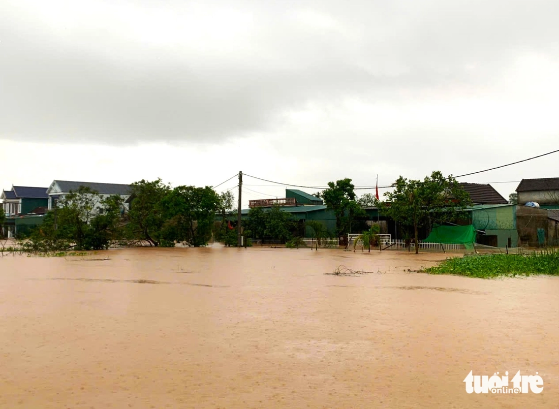 Mưa lớn và lũ đổ về khiến làng mạc bị cô lập, đường sá chìm trong biển nước - Ảnh 1.