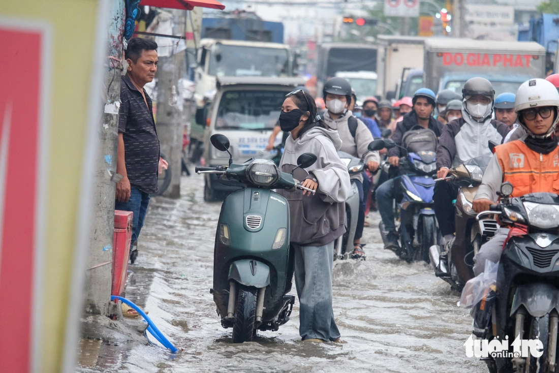Quốc lộ 50 ‘chìm’ trong triều cường, người dân chung tay căng bạt, đắp cát ngăn nước- Ảnh 1. Đường Văn Tiến Dũng ‘chìm’ trong triều cường, người dân chung tay căng bạt, đắp cát ngăn nước - Ảnh 1.