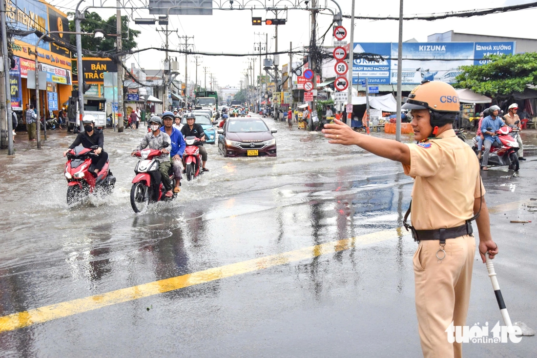 Quốc lộ 50 ‘chìm’ trong triều cường, người dân chung tay căng bạt, đắp cát ngăn nước- Ảnh 3. triều cường - Ảnh 3.