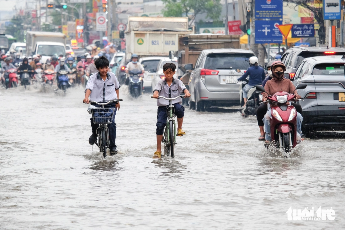Quốc lộ 50 ‘chìm’ trong triều cường, người dân chung tay căng bạt, đắp cát ngăn nước- Ảnh 4. triều cường - Ảnh 4.