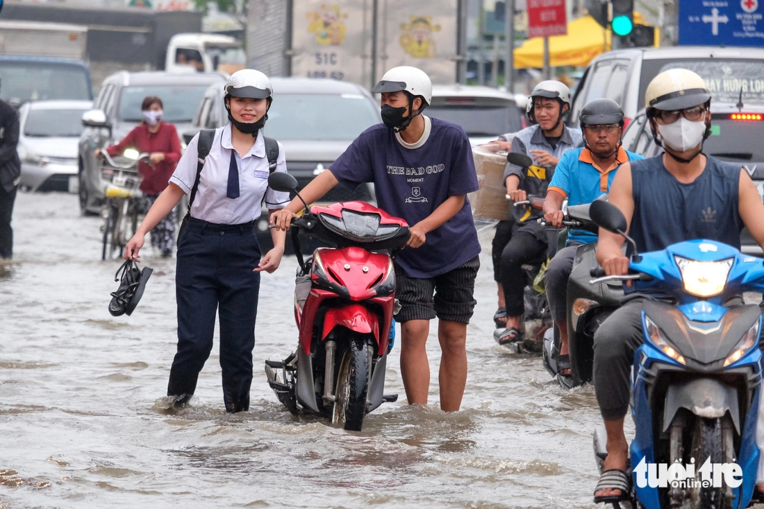Quốc lộ 50 ‘chìm’ trong triều cường, người dân chung tay căng bạt, đắp cát ngăn nước- Ảnh 5. triều cường - Ảnh 5.