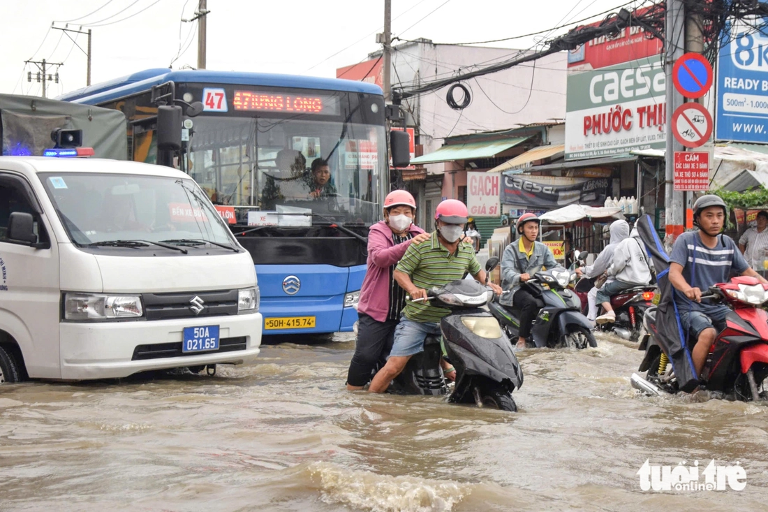 Quốc lộ 50 ‘chìm’ trong triều cường, người dân chung tay căng bạt, đắp cát ngăn nước- Ảnh 6. triều cường - Ảnh 6.