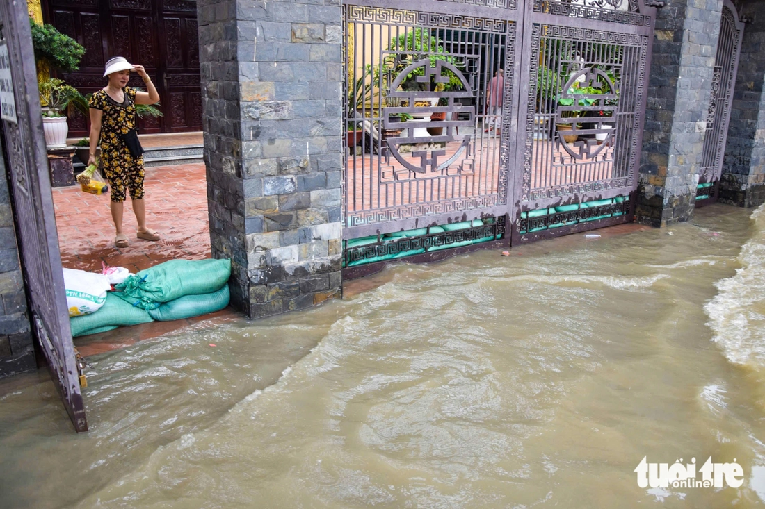 Quốc lộ 50 ‘chìm’ trong triều cường, người dân chung tay căng bạt, đắp cát ngăn nước- Ảnh 9. triều cường - Ảnh 9.