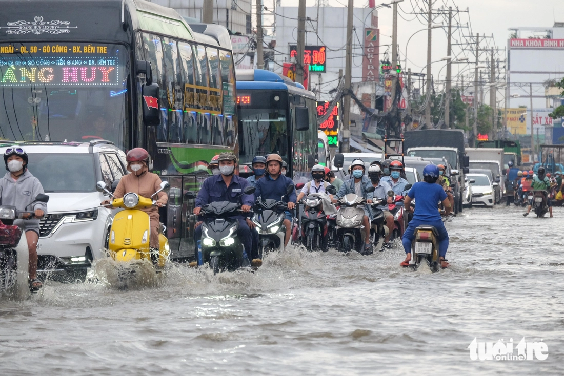 Quốc lộ 50 ‘chìm’ trong triều cường, người dân chung tay căng bạt, đắp cát ngăn nước- Ảnh 10. triều cường - Ảnh 10.