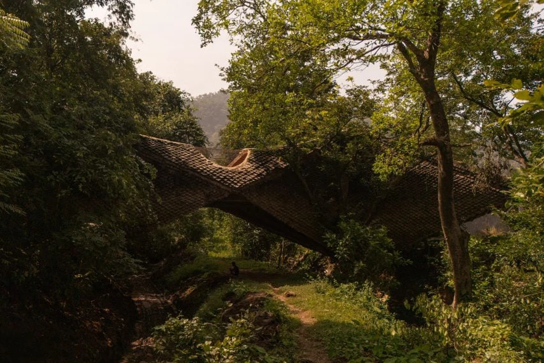 Nhà cầu bắc qua khe nước với lớp 'vảy tê tê' bằng bùn tranh kỳ lạ - Ảnh 2.