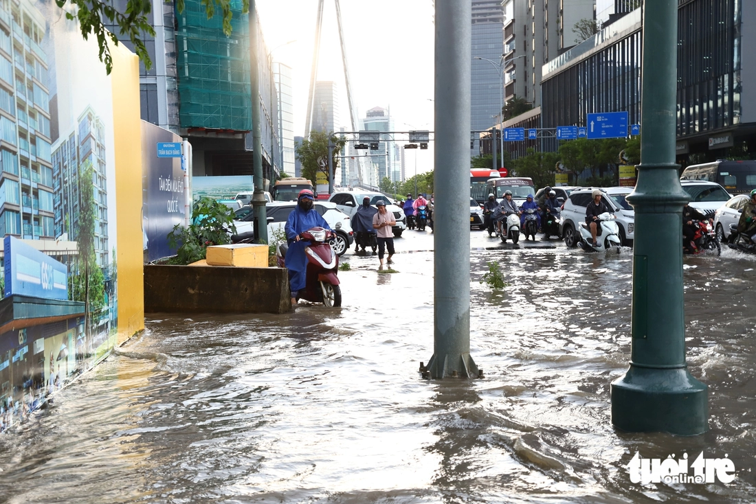 Đường ngập sau cơn mưa lớn ở TP.HCM, người dân vất vả dắt xe máy giữa dòng nước - Ảnh 3.